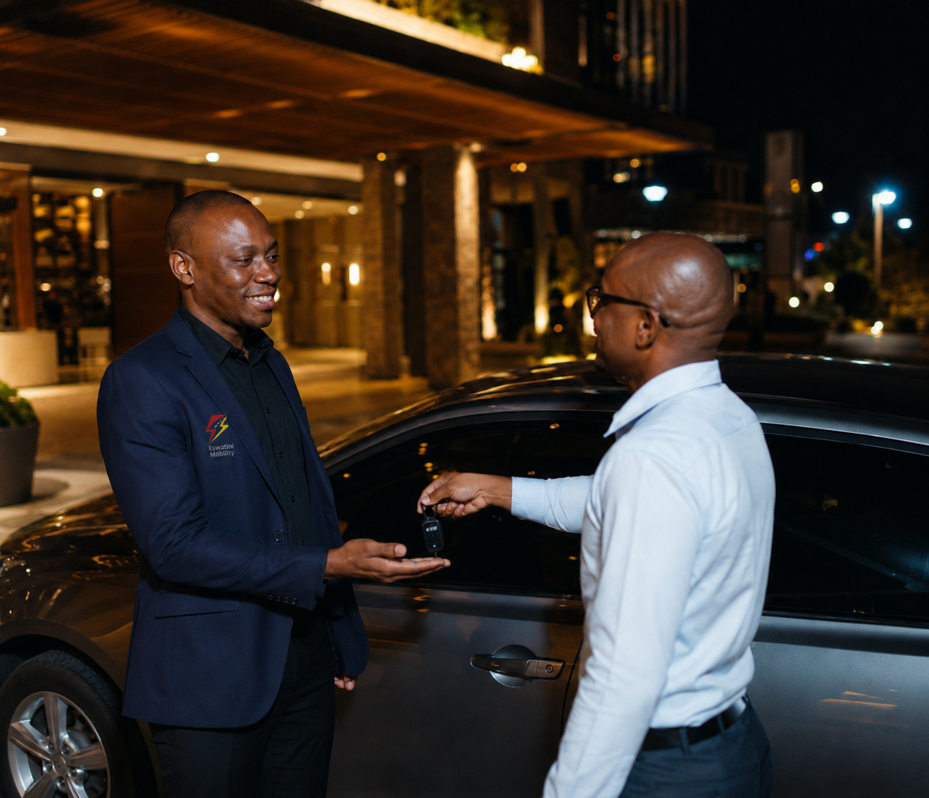 Professional SafeRide driver handing car keys to a client outside a hotel at night